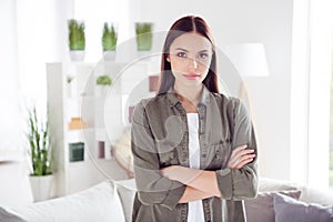 Photo of serious confident young lady wear green shirt standing arms folded indoors room home