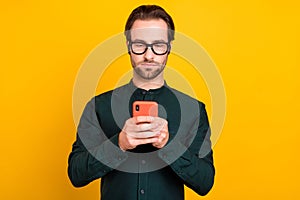 Photo of serious confident young man wear smart casual outfit glasses chatting modern device isolated yellow color