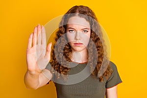 Photo of serious girl showing arm palm stop sign keep distance symbol isolated on yellow color background