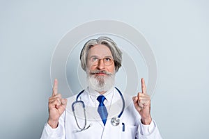 Photo of serious intelligent mature male doctor wear white coat glasses looking pointing up empty space isolated grey