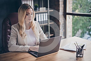 Photo of serious pondering business consulter browsing through her laptop in search of new customers and clients to be