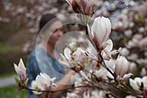 Photo session of a young woman among a blooming magnolia