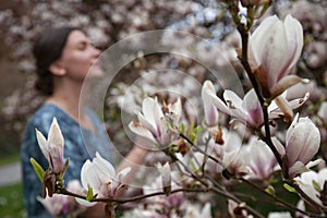 Photo session of a young woman among a blooming magnolia