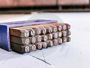 Photo a set of alphabetical steel punches in blue plastic box.