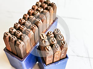 Photo a set of numirecal and alphabetical steel punches in blue plastic box.