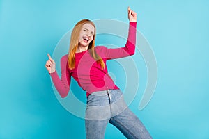 Photo of shiny funky young woman wear pink shirt dancing pointing fingers empty space smiling isolated blue color