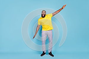 Photo of shiny pretty dark skin guy dressed yellow t-shirt smiling dancing isolated blue color background