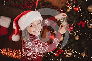 Photo of shiny sweet school girl wear print pullover headwear smiling hanging new year balls indoors house home room