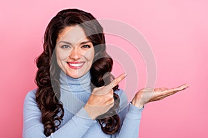 Photo of shiny sweet woman wear blue sweater holding arm pointing empty space isolated pink color background photo