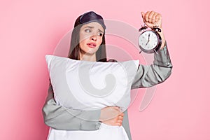 Photo of shiny unhappy young lady sleepwear holding pillow looking retro timer isolated pastel pink color background