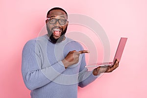 Photo of shocked afro guy wear grey pullover glasses pointing modern device isolated pink color background photo