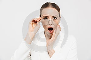 Photo of shocked businesswoman 20s wearing elegant jacket looking at camera and holding eyeglasses