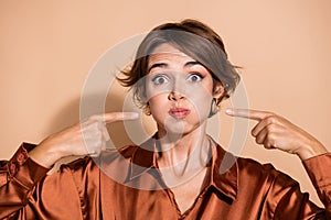 Photo of shocked funky lady dressed silky shirt fingers pressing bloated cheeks isolated beige color background