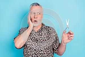 Photo of shocked old grandfather look hold hand scissors cheekbone isolated on pastel blue color background photo