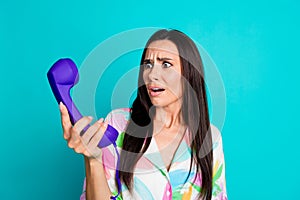 Photo of shocked woman wear stylish print clothes hold telephone landline stupor panic isolated on cyan color background