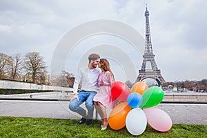 Photo shoot, happy couple with balloons posing near Eiffel tower in Paris