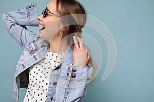 Photo shot of attractive happy smiling young blonde woman wearing summer casual clothes and stylish sunglasses isolated