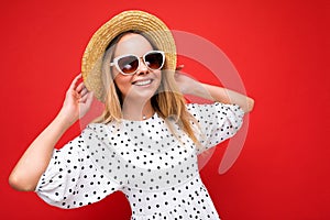 Photo shot of attractive happy smiling young blonde woman wearing summer casual clothes and stylish sunglasses isolated