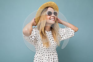 Photo shot of attractive happy smiling young blonde woman wearing summer casual clothes and stylish sunglasses isolated