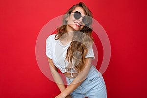 Photo shot of beautiful happy smiling young blonde woman wearing casual clothes and stylish sunglasses  over