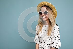 Photo shot of beautiful positive young blonde woman wearing summer casual clothes and stylish sunglasses isolated over