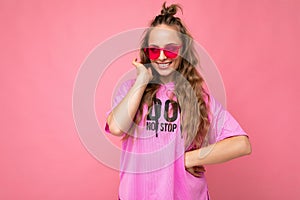 Photo shot of beautiful smiling young dark blonde woman wearing casual clothes and stylish sunglasses isolated over