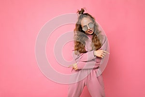 Photo shot of beautiful young dark blonde woman wearing casual clothes and stylish sunglasses isolated over colorful