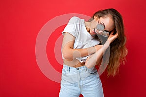 Photo shot of beautiful young positive dark blonde woman wearing casual clothes and stylish sunglasses isolated over