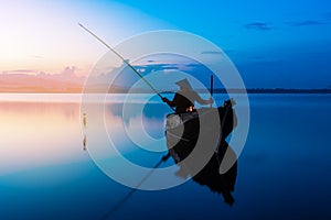 Photo shot fisherman throwing fishing net on the lake. Silhouette of fisherman with fishing net in morning sunshine.