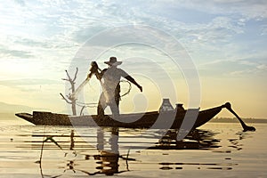 Photo shot of water spatter from fisherman while throwing fishing net on the lake. Silhouette of fisherman with fishing net in