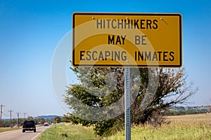 Sign with the inscription \'Hitchikers May be Escaping Inmates\' photo
