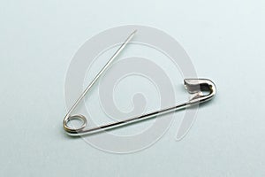 Photo of silver safety pin isolated on blue background