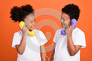 Photo of small funky girl boy talk telephone wear white t-shirt isolated on orange background