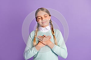 Photo of small grateful girl closed eyes crossed hands chest wear green sweater  purple background