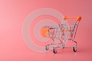 Photo of small silver shopping cart isolated over pink color pastel background with copy empty blank space