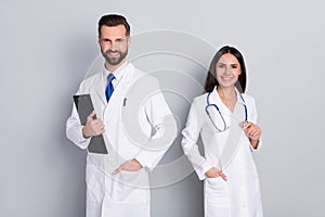 Photo of smart clever two docs dressed white coats holding clipboard isolated grey color background