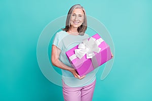 Photo of smiling cheerful nice looking mature woman grandmother hold birthday present isolated on teal color background