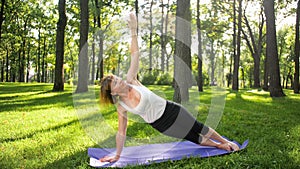 Photo of smiling happy woman 40 years old doing yoga exercises on fitness mat at forest. Harmony of human in nature