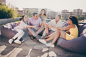 Photo of smiling positive happy excited cheerful group of young people make toast celebrate success outside on rooftop