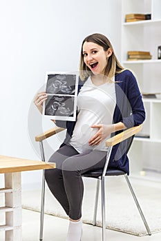 Photo of smiling pregnant woman holding ultrasound result.