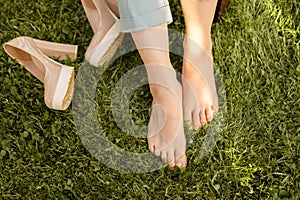 Photo of some feet resting from high heels on fresh green grass on day time.