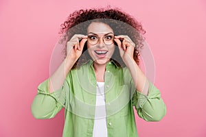 Photo of speechless smart woman with perming coiffure dressed shirt astonished staring touching glasses isolated on pink