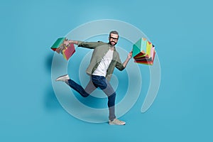 Photo of sporty handsome guy jump carry outfit packages run wear specs green shirt isolated blue color background