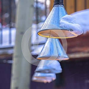 Photo Square Cone shaped string lights with snow hanging outside a home in winter