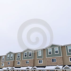 Photo Square frame Exterior of townhouses with gable roofs and brick wall against cloudy sky