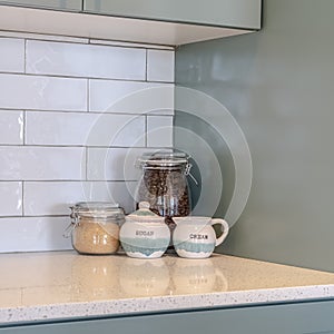 Photo Square frame Jars of coffee beans sugar and cream on a countertop with tile backsplash