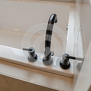 Photo Square frame Matte black faucet and handles on a glossy clean white built in bathtub