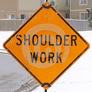 Photo Square frame Shoulder Work sign on the snowy sidewalk of road under construction in winter