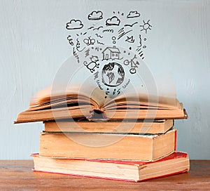 Photo of stack of books over wooden table. top book is open with set of infographics icons. create a better world concept or