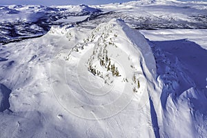 Photo of standalone big mountain in Scandinavia, cold sunny day, blue sky, closer aerial photo of wild subarctic nature taken from